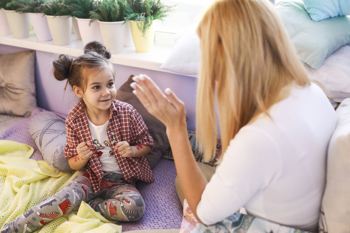 A young girl in conversation during a therapy session, smiling and engaged.