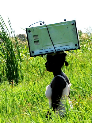 a lady carrying a microwave to...somewhere with electricity!